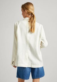 Blazer in lino bianco sporco, con vestibilità rilassata, revers a lancia e chiusura a un bottone. Il retro presenta una cucitura centrale e polsini con bottone.