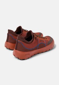 Red and brown sneakers with a textured knit upper, blue accents, and rubber soles featuring a tread pattern. Laces and logo detail present.