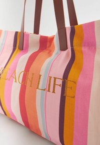 Geantă tote din pânză cu dungi multicolore în roz, portocaliu și galben. Prezintă mânere din piele maro și broderie aurie cu textul "BEACH LIFE".
