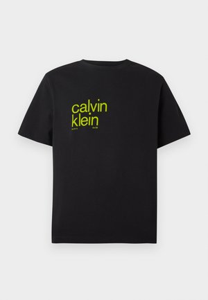 Schwarzes Baumwoll-T-Shirt mit gelber Schrift, die "calvin klein" und "new york city since 1968" in einer modernen, fetten Schriftart zeigt. Kurze Ärmel.