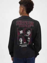 Tricou negru cu mâneci lungi, având pe spate un grafic „Stranger Things” cu patru portrete de personaje și accente roșii. Material din bumbac.