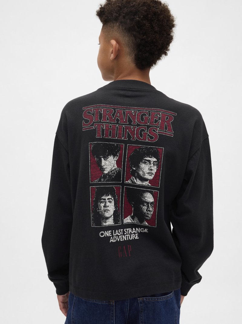 Tricou negru cu mâneci lungi, având pe spate un grafic „Stranger Things” cu patru portrete de personaje și accente roșii. Material din bumbac.