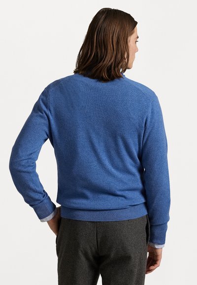 Blauwe trui van zacht materiaal, met een geribbelde boord en boorden. De achterkant heeft een eenvoudig ontwerp zonder patronen of versieringen.