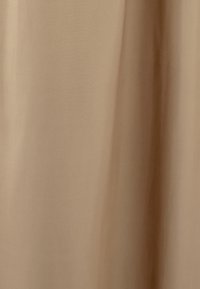 Beige stof met een gladde textuur, die zacht valt. Het oppervlak is effen met subtiele kleurvariaties, wat een minimalistisch ontwerp uitstraalt.