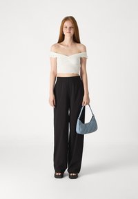 Balts off-shoulder īsais tops ar volānu apdari, melni platleņķa bikses un zila džinsu rokassoma ar teksturētu rakstu un pleca siksnu.
