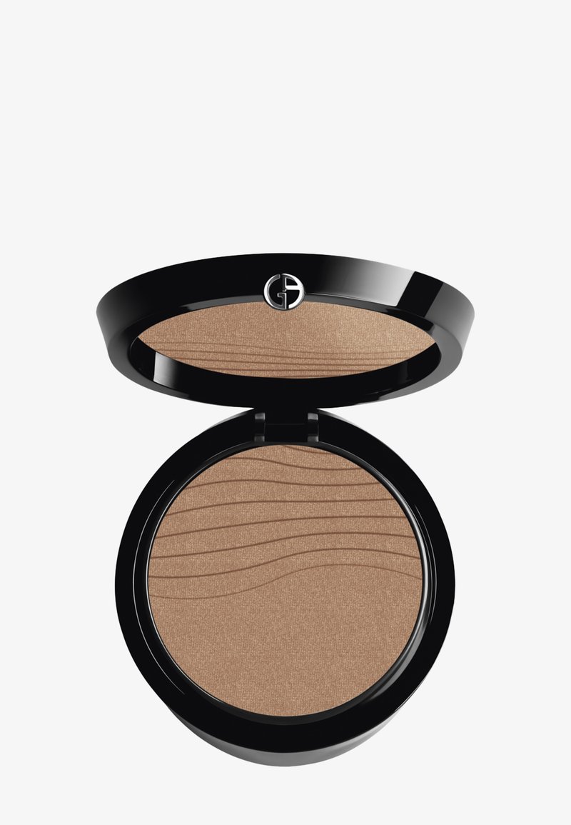 Bronzer compatto in un elegante astuccio nero lucido. Presenta una superficie in polvere pressata con un motivo a onda testurizzato. Il colore è un marrone chiaro con scintillio.