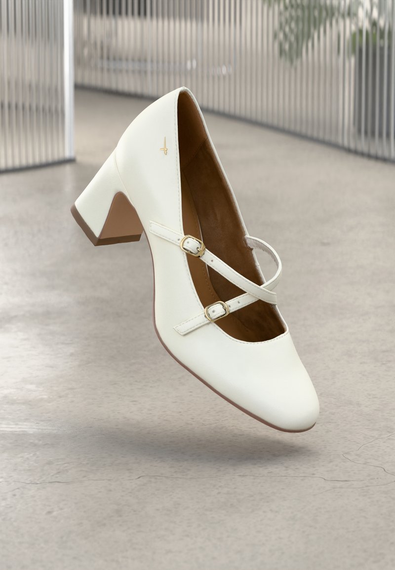 Escarpin Mary Jane en cuir blanc avec un talon carré, doté de deux brides réglables et d'un accent doré. Texture lisse avec un design à bout arrondi.