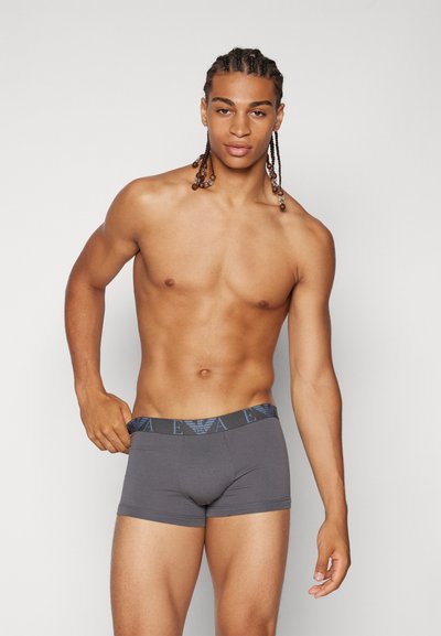 Boxer shorts grises con una cinturilla azul con logo, fabricados en un material suave. El diseño presenta un ajuste ceñido y un corte de altura media.