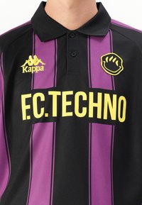 Mustapohja ja purppuran värinen polo-paita, jossa on pystysuorat raidat. Varustettu keltaisella "F.C.TECHNO" -logolla ja Kappa-embleemilla. Pehmeä ja kevyt kangas.