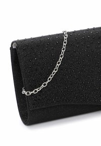 Svart kuvertväska i texturerad tyg, prydd med en silverkedja och små svarta dekorationer på ytan.