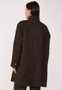 Cappotto marrone dalla trama con colletto alto, maniche lunghe e dettagli con bottoni. Vestibilità sagomata, realizzato in un tessuto spesso e intrecciato.