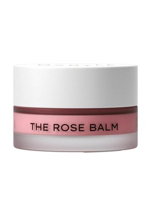 Lille klar glasbeholder med lyserød balsam indeni og hvidt tekstureret låg med etiketten "THE ROSE BALM" på fronten.