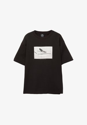 Fekete pamut póló rövid ujjakkal, fehér téglalap alakú grafikus mintával egy légyről vékony vonalon, minimalista logóval a kép alatt.