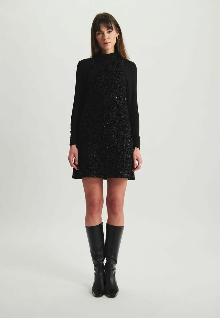 Robe noire à sequins avec une silhouette ajustée et un design sans manches, associée à des bottes noires montantes. Texture lisse et accents brillants.