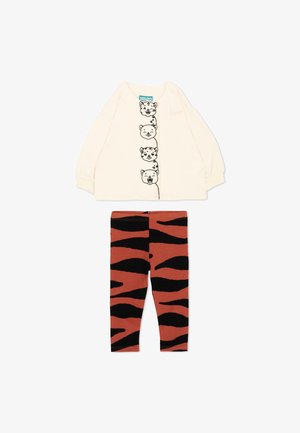 Crèmewit shirt met lange mouwen met vier zwarte omrande dierengezichten aan de voorkant en oranje legging met zwart tijgerstrepenpatroon.