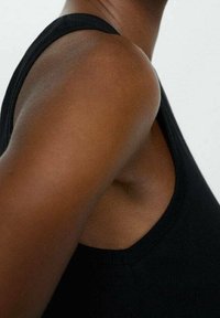 Débardeur noir sans manches avec un col rond, présentant une texture douce et lisse ainsi qu'une coupe ajustée, mettant en valeur l'épaule et le haut du bras.