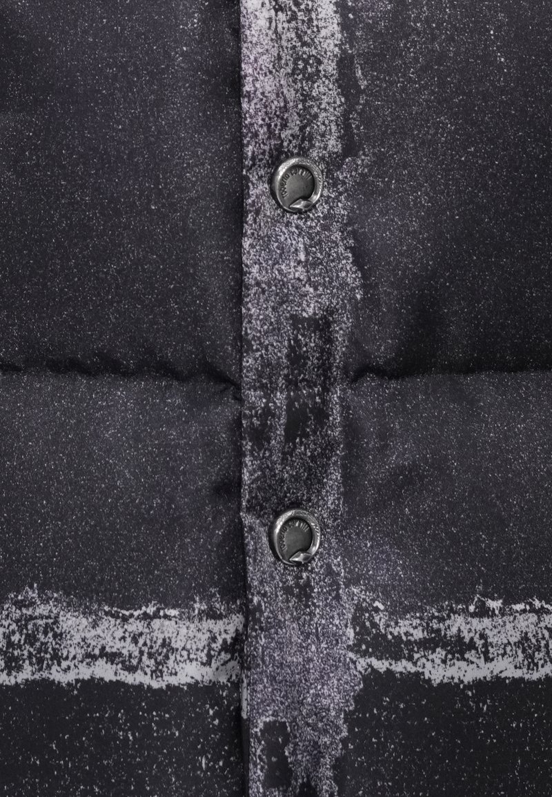 Sort mønstret puffjakke i stof med en tekstureret overflade, knapper og synlige linjer i kontrasterende nuancer af grå og hvid.