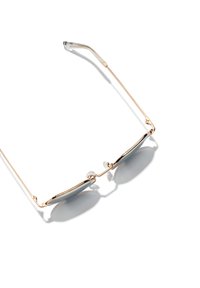 Gafas de sol de metal dorado con lentes grises, con montura delgada y almohadillas nasales, que presentan una forma geométrica y delicadas puntas de las patillas transparentes.