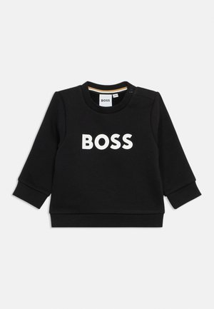 Črna kapuca iz bombaža, z dolgimi rokavi in okroglim ovratnikom. Na sprednji strani je bel natisnjen logotip "BOSS". Detajl s pritisnim gumbom na ramenu.