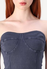 Top senza bretelle a coste blu navy con un design aderente, dettagli delle cuciture curve, texture morbida e lucentezza sottile.