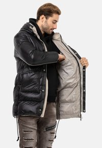 Schwarze Daunenjacke mit Kapuze und kontrastierender Innenausstattung. Verfügt über einen Reißverschluss, Fronttaschen und Kordelzüge am Saum.