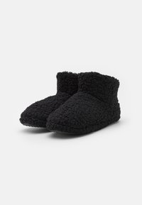 Black slipper boots made of textured, fuzzy material; low ankle design with a soft, cozy appearance and curved toe shape.