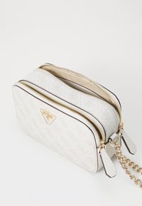 Borsa a tracolla bianca con texture, accessori in oro, doppie compartimenti e dettaglio del logo iconico sulla parte anteriore. Presenta una tracolla a catena.