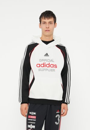Hvid og sort hoodie med røde detaljer, der har et oversized "adidas" logo og teksten "OFFICIAL SUPPLIER". Tre striber på ærmerne.