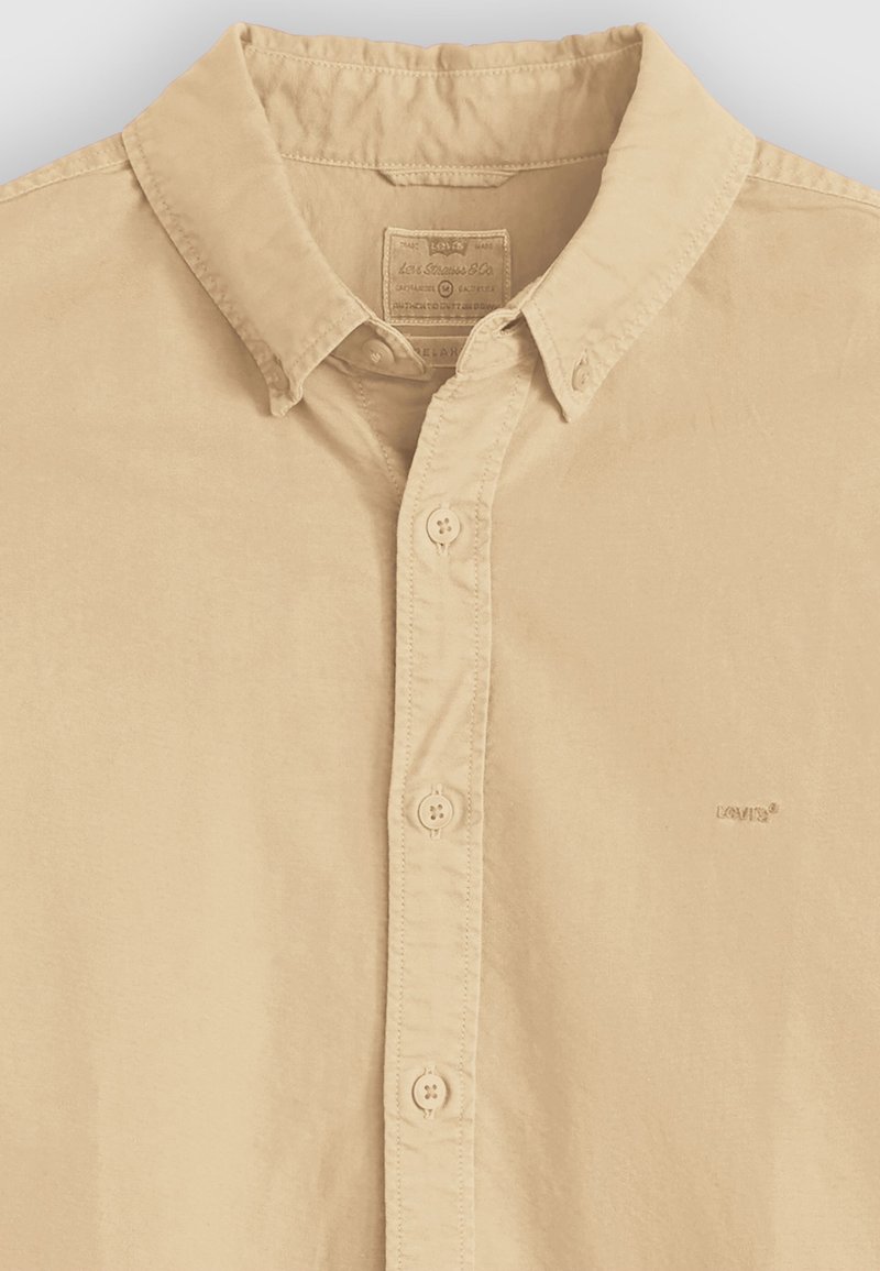 Beiges Hemd mit Knopfleiste, spitzem Kragen, drei sichtbaren Knöpfen und einem kleinen auf der Brust gestickten Levi's-Logo.