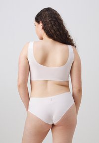 Lys beige bh og matchende truser laget av glatt, elastisk stoff. Moderat dekning med brede stropper og et enkelt design.