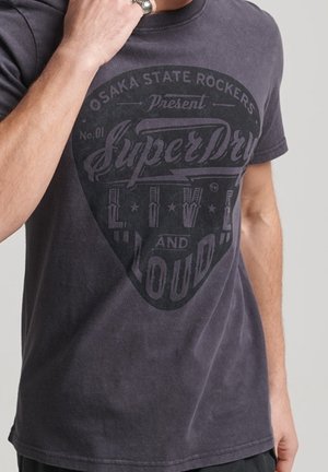 Ciemnoszary bawełniany t-shirt z vintage'owym czarnym nadrukiem z napisem "SuperDry" i gwiazdkami. Okrągły dekolt i krótkie rękawy.