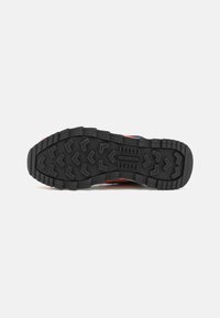 Semelle en caoutchouc avec un motif de crampons profonds, des grips en forme de chevron et un marquage "Merrell" au centre pour l'adhérence et la durabilité.