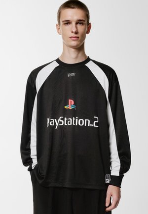 Black long-sleeve shirt featuring white raglan sleeves. Front displays "PlayStation 2" logo with multicolored emblem. Smooth fabric texture.
