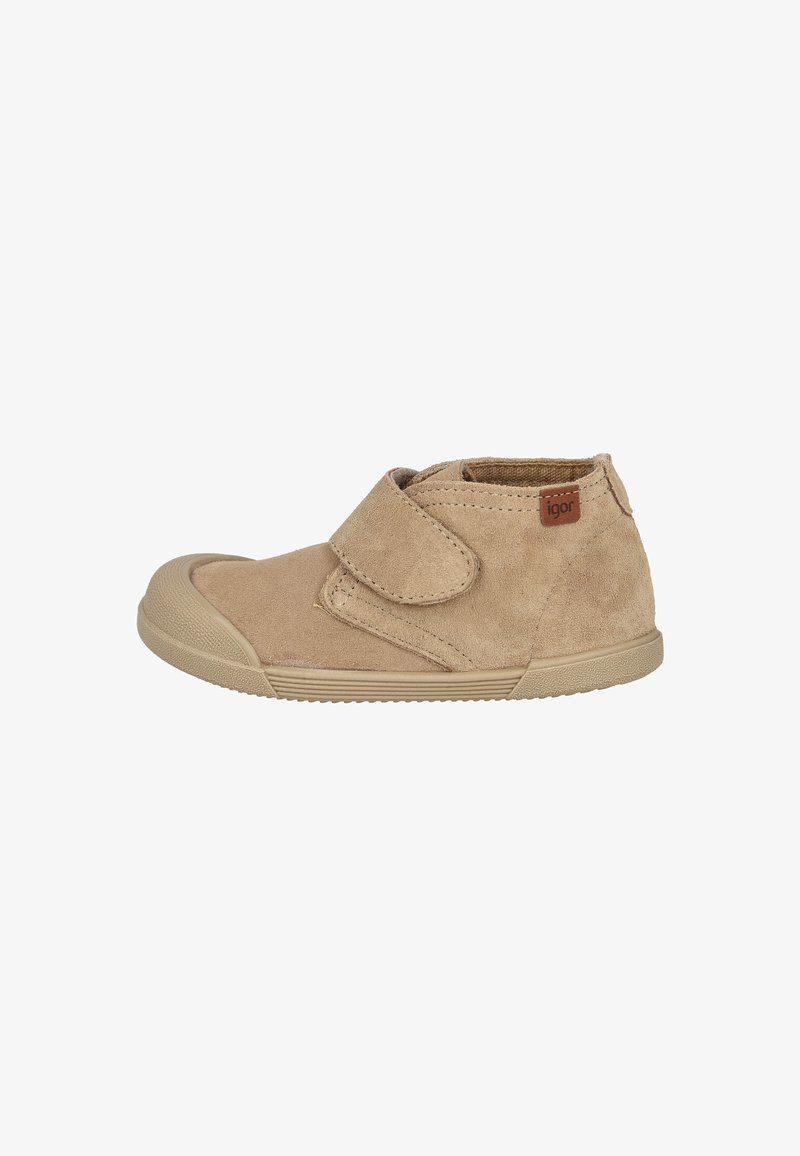 Zapato infantil de ante beige con suela de goma y puntera, asegurado por una amplia correa de velcro, que presenta una pequeña etiqueta marrón "igor".