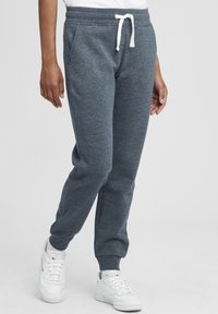 Grå bomulls joggebukser med snor i midjen, sidelommer og ribbestrikkede mansjetter. Kombinert med hvite sneakers, som fremhever en avslappet stil.