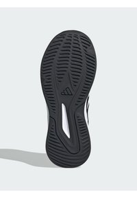 Semelle en caoutchouc noir avec motif de grip texturé, dotée d'une semelle intermédiaire blanche. Le design comprend un logo et une surface non marquante.