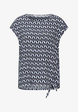 Haut à manches courtes, ample, fabriqué en tissu léger. Présente un motif en diamants navy et blancs avec un accent noué à l'ourlet.