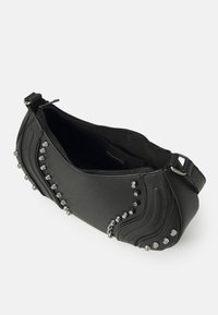 Black leather handbag featuring silver studs along one side, curved stitching detail, and zip closure. Interior is solid black.