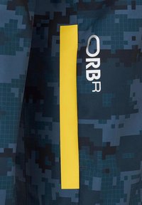 Niebieska tkanina w wzory z cyfrowym kamuflażem, żółtą pionową paską oraz białym logo "ORBR" po boku.