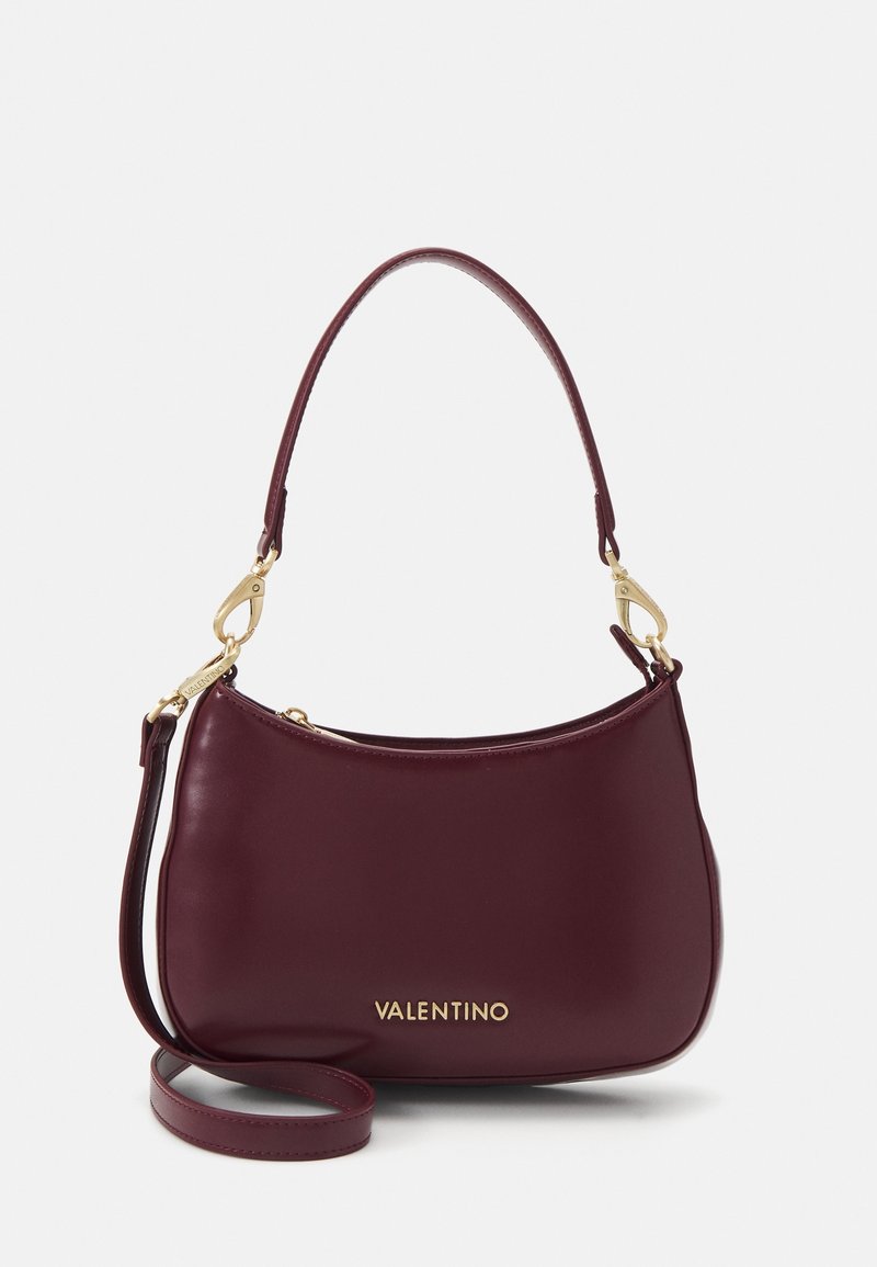 Burgundy läderhandväska med en böjd design, guldhardware detaljer, justerbar axelrem och präglad "Valentino" logotyp.