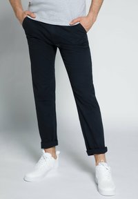 Chinos blu navy realizzati in cotone con una vestibilità dritta, dotati di risvolti, tasche laterali e abbinati a sneaker bianche.