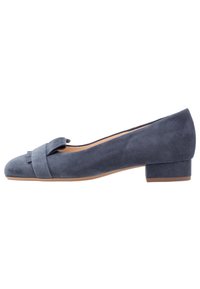 Scarpa piatta in suede grigio con punta arrotondata e un dettaglio a fiocco decorativo sul davanti. Presenta un tacco basso a blocco per maggiore stabilità.