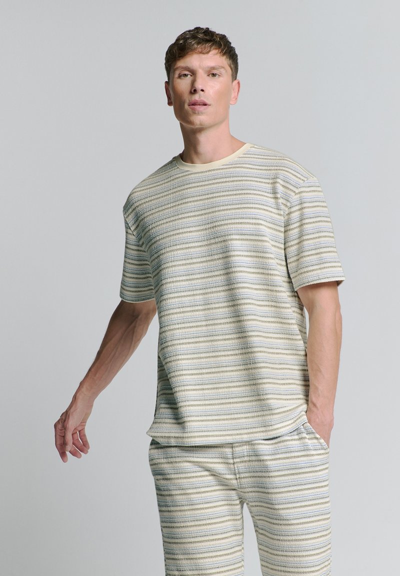Gestreept gebreid T-shirt in crèmekleurige, beige en blauwe tinten. Korte mouwen, ronde hals, relaxte pasvorm, textuurstof met horizontale strepen.