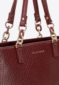 Sac à main en cuir bordeaux avec une surface texturée. Équipé de quincaillerie en ton doré et d'accents en chaîne. "Wittchen" embossé à l'avant.