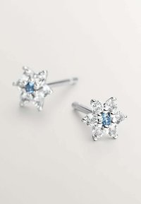 Pendientes de plata con forma de flor, con una piedra azul en el centro, rodeada de piedras transparentes, y con un acabado pulido.
