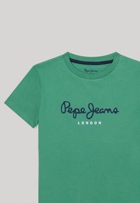 Zielona koszulka z krótkim rękawem wykonana z bawełny. Zawiera niebieskie logo "Pepe Jeans" oraz białe napisy "LONDON" poniżej. Okrągły dekolt.