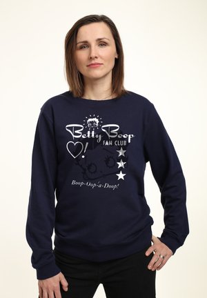 Marineblå sweatshirt med grafik af Betty Boop, teksten "Betty Boop Fan Club" og sølvfarvede stjerner. Materialet ser blødt ud og har lange ærmer.
