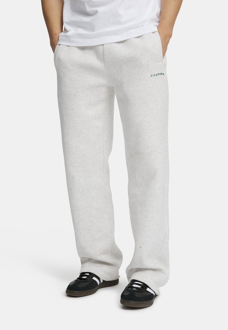 Lys grå joggebukser laget av myk stoff, med sidelommer og en liten grønn logo på forsiden. Løs passform med rette ben.