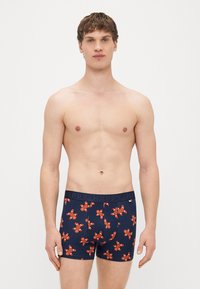 Boxers masculinos em tecido azul-marinho com padrão de bonecos de gengibre vermelhos. Cintura elástica com o texto "HAPPY". Design ajustado e elástico.