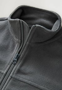 Graue Fleecejacke mit hohem Kragen, halbem Reißverschluss und Flachnaht-Nähten. Strukturiertes Material und kontrastierendes Reißverschlussdetail.